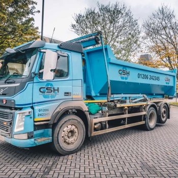 Side view of blue CSH Environmental lorry with waste container